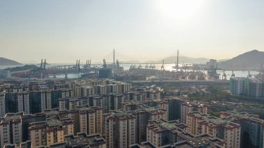 Yükselen malikane, parlayan sisli güneş ışığının altındaki konteynır limanına bakıyor, 16 Şubat 2026