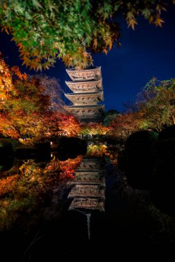 Parlak beş katlı pagoda canlı bir sonbahar yeşilliği ile aynalanmış 25 Kasım 2025