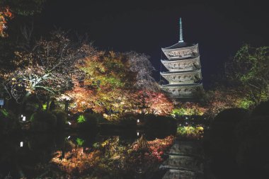 Parlak beş katlı pagoda canlı bir sonbahar yeşilliği ile aynalanmış 25 Kasım 2025