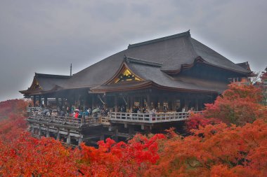 Tarihsel ahşap salon canlı sonbahar yeşillikleri tarafından çerçevelenmiş 25 Kasım 2025