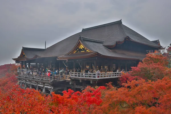 Tarihsel ahşap salon canlı sonbahar yeşillikleri tarafından çerçevelenmiş 25 Kasım 2025