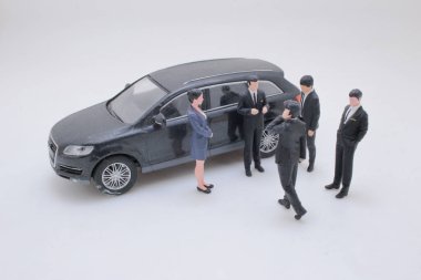 Koyu renk dört kapılı araba kopyası etrafında küçük bir grup oluşturuldu.