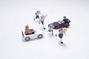 Oyuncak figürler iki minyatür araca neşeyle yaklaşıyorlar.