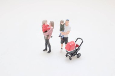 Küçük heykelcikler, çocukları parlak bebek arabasının yanında tutan yetişkinleri resmediyor.