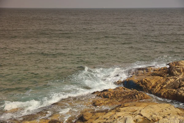 Klippig havskust och suddigt vatten i shek o, hong kong — Stockfoto