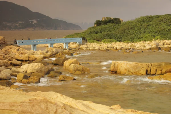 Rotsachtige kust en wazig water in shek o, hong kong — Stockfoto