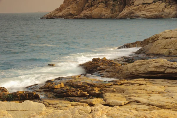 Rotsachtige kust en wazig water in shek o, hong kong — Stockfoto