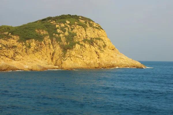 Rotsachtige kust en wazig water in shek o, hong kong — Stockfoto