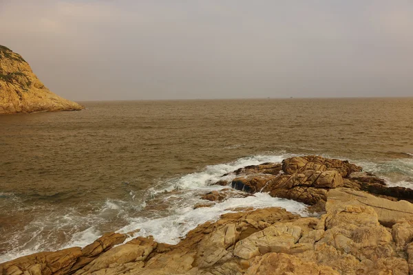 Felsige Meeresküste und verschwommenes Wasser in shek o, hong kong — Stockfoto