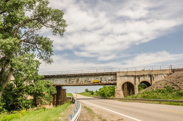 Rusty ponte ferroviária sobre a estrada do país — Fotografia de Stock