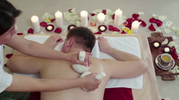 Mann im Kurort Massagebeutel mit aromatischen Kräutern — Stockvideo