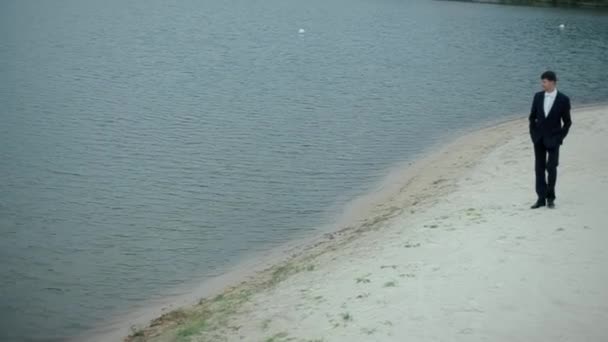 Человек идет вдоль берега озера — стоковое видео