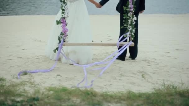 Бег жениха и невесты от качелей к озеру — стоковое видео