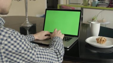 bir adam türleri masasının üzerindeki bir laptop.