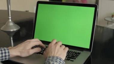 bir adam türleri masasının üzerindeki bir laptop.