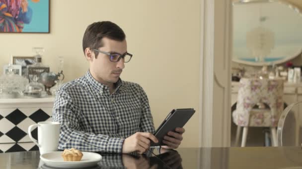 Un jeune homme regarde à travers sa tablette comme il secoue — Video