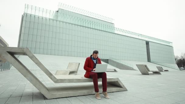 Молодой человек работает на современном ноутбуке на открытом воздухе — стоковое видео