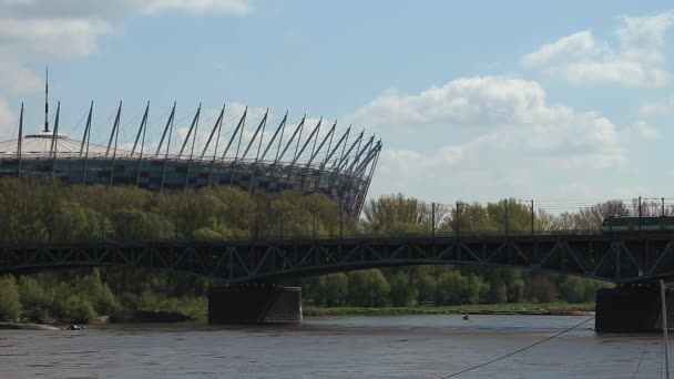 Tåget passerar på en bro på bakgrund av Stadium — Stockvideo