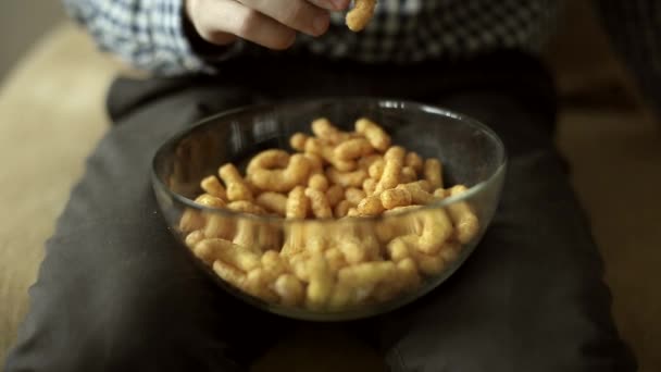 Чоловік сидить на дивані і їсть кукурудзяні закуски — стокове відео
