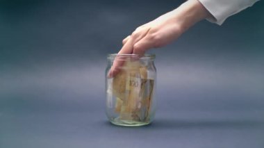Kadın koyar Kanada Doları 100 bir cam kavanoza