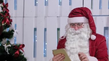 Noel Baba satın almak ve dijital tablet odada Noel ağacı ve hediyeler ile ödeme