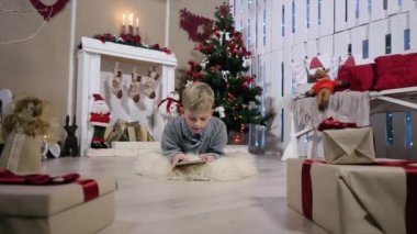 Çocuk dijital tablet için bir hediye seçer, kamera bir çocuk, Şömine ve Noel Ağacı ile beyaz Oda taşınır