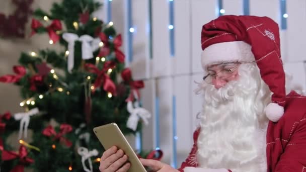 Санта працює на цифровий планшет, подарунки Різдвяна ялинка. — стокове відео