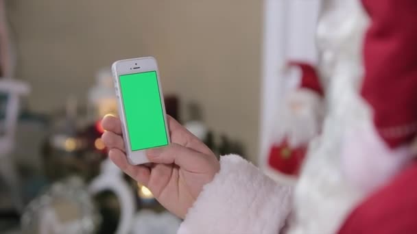 Papai Noel usando telefone com tela verde em casa. Smartphone com tela verde no modo vertical. Fácil de rastrear e digitar. Codec de QG ProRes — Vídeo de Stock