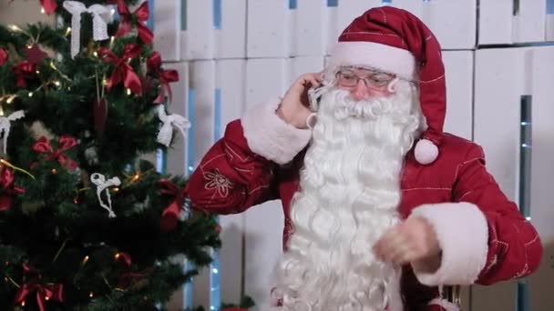 Santa Claus hablando su Smatrphone en la habitación con árbol de Navidad y regalos — Vídeos de Stock