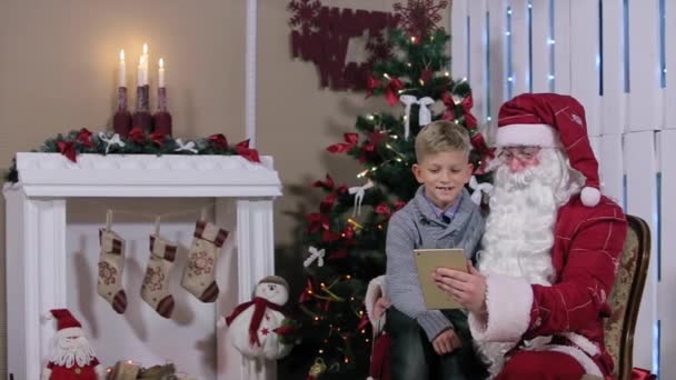 Little Boy Chooses a Gift from Santa on Tablet in Hand — Stock Video