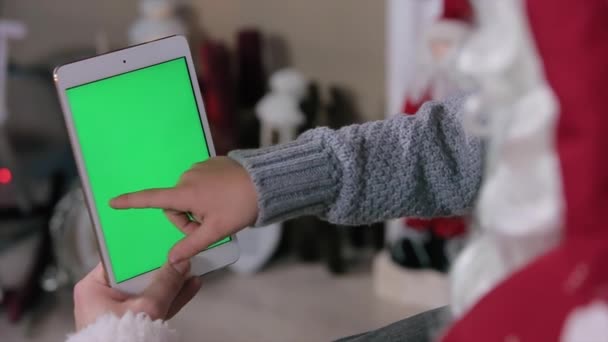 Der Weihnachtsmann und der kleine Junge wählen Geschenke auf Tablets aus. Tablet mit grünem Bildschirm im vertikalen Modus. leicht zu verfolgen und zu tasten. prores hq codec — Stockvideo