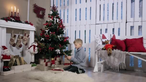 Niño Para hablar a través de tableta digital, Habitación blanca con chimenea y árbol de Navidad — Vídeo de stock