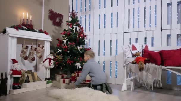 The boy ran to the tree, extracts from phone boxes, white Room with Fireplace and Christmas Tree — Stock Video