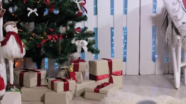 Der Junge rannte zum Baum, ist eine Schachtel mit Geschenk, offene Schachtel, zieht und überlegt digitales Tablet, weißes Zimmer mit Kamin und Weihnachtsbaum, mittel — Stockvideo