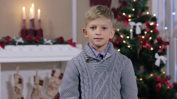 Kleine jongen weergegeven duim omhoog, glimlachend, witte kamer met open haard en kerstboom, medium — Stockvideo