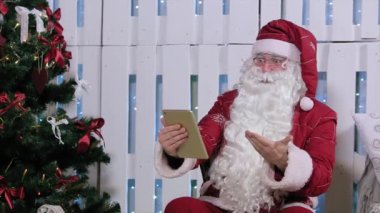 Noel Baba olduğunu Sit ve parmak kadar dijital Tablet, şömine ve Noel ağacı, hediyeler Oda.