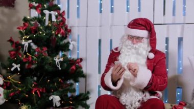 Noel Baba oturmak ve onun telefon, Şömineli Oda ve Noel ağacı, hediyeler.