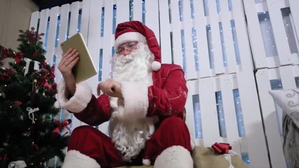 Pantalla táctil tipo Santa en la sala de tabletas con chimenea y árbol de Navidad . — Vídeos de Stock