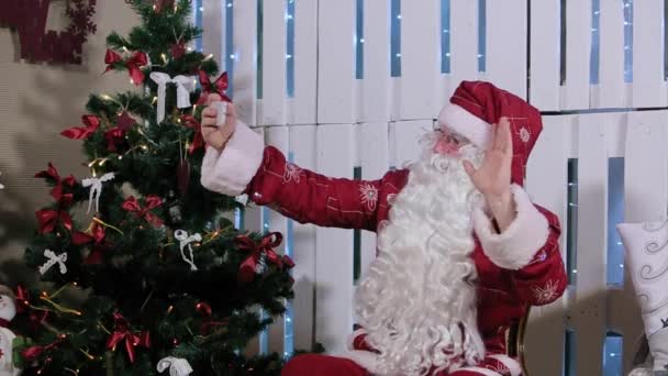 Papai Noel é sentar e fazer Selfi seu smartphone, quarto com lareira e árvore de Natal, presentes . — Vídeo de Stock