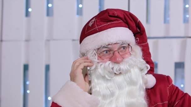 Santa Claus Talking His Smatrphone in Room with Christmas Tree and Gifts — Stock Video