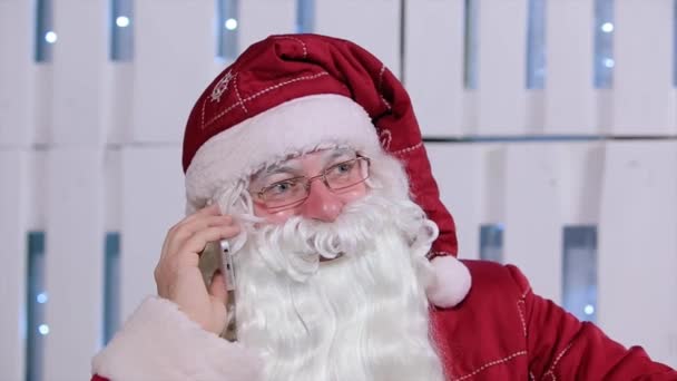 Santa Claus hablando su teléfono en la habitación con el árbol de Navidad y regalos — Vídeos de Stock