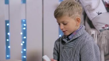 Noel ağacının yanında oturan bir çocuk, onu görme elinde akıllı telefon döner, Şömine ve Noel Ağacı ile beyaz Oda, Close Up, insanlar