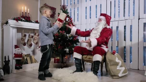 Boy is Present Santa and Shakes His Ear and Santa waving hands — Stock Video