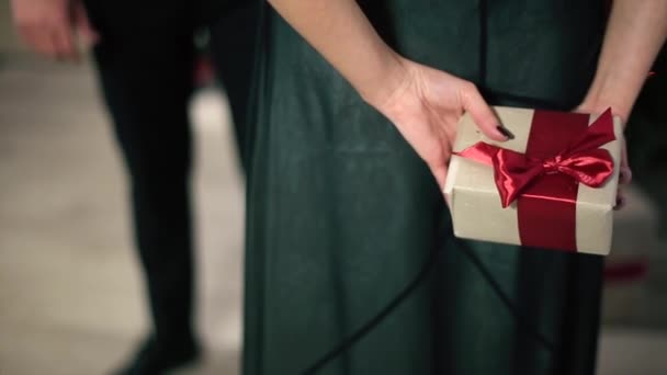 Женщина в вечернем платье держит в руках подарок с красной лентой — стоковое видео