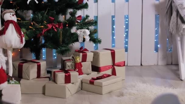 Le garçon couru à l'arbre, est une boîte avec un cadeau, secoue, tire et considère smartphone, Chambre blanche avec cheminée et arbre de Noël, Moyen — Video