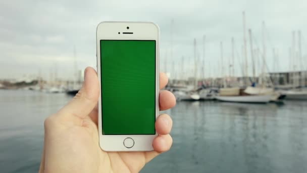 Зеленый экран смартфона на фоне яхт — стоковое видео