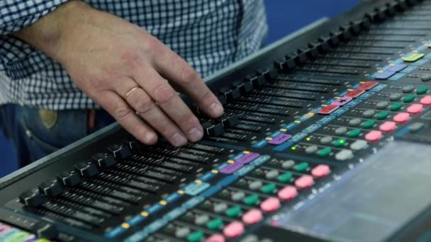 Un ingeniero de sonido Usando un escritorio de mezcla o una consola de mezcla para mezclar una pista en un estudio de grabación. Con luces de nivel y sobrecarga, fundidores y botones de macetas — Vídeos de Stock