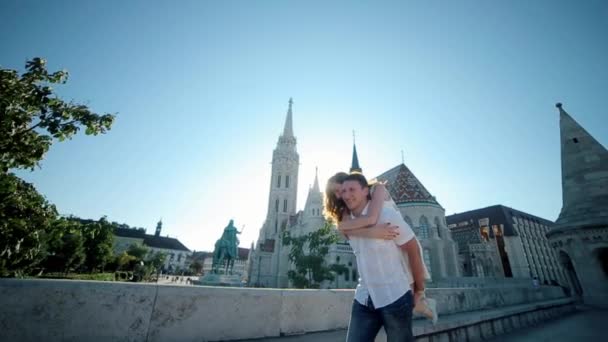 Jonge Man gedragen op de schouders van de achtergrond van een vrouw spinnen glimlach Matthias kerk — Stockvideo