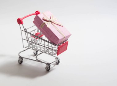 Beyaz arka planda küçük bir alışveriş arabasında bir kutu elma rengi.