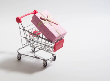 Beyaz arka planda küçük bir alışveriş arabasında bir kutu elma rengi.